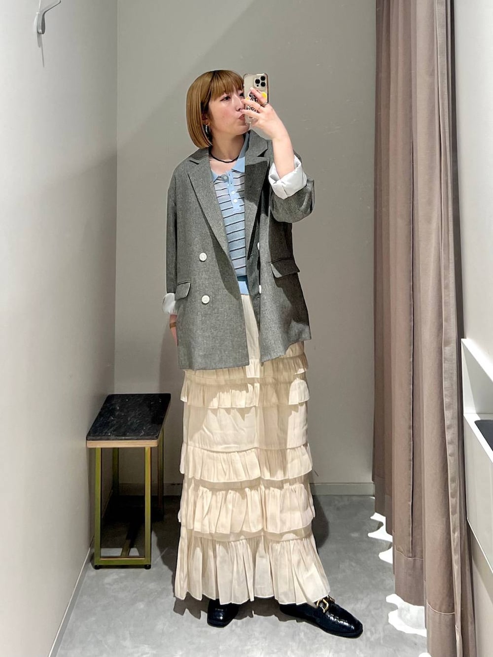 グレー系のテーラードジャケット、ホワイト系のスカート、ブルー系のポロシャツを着用したレディースの春コーディネートの5枚目の写真