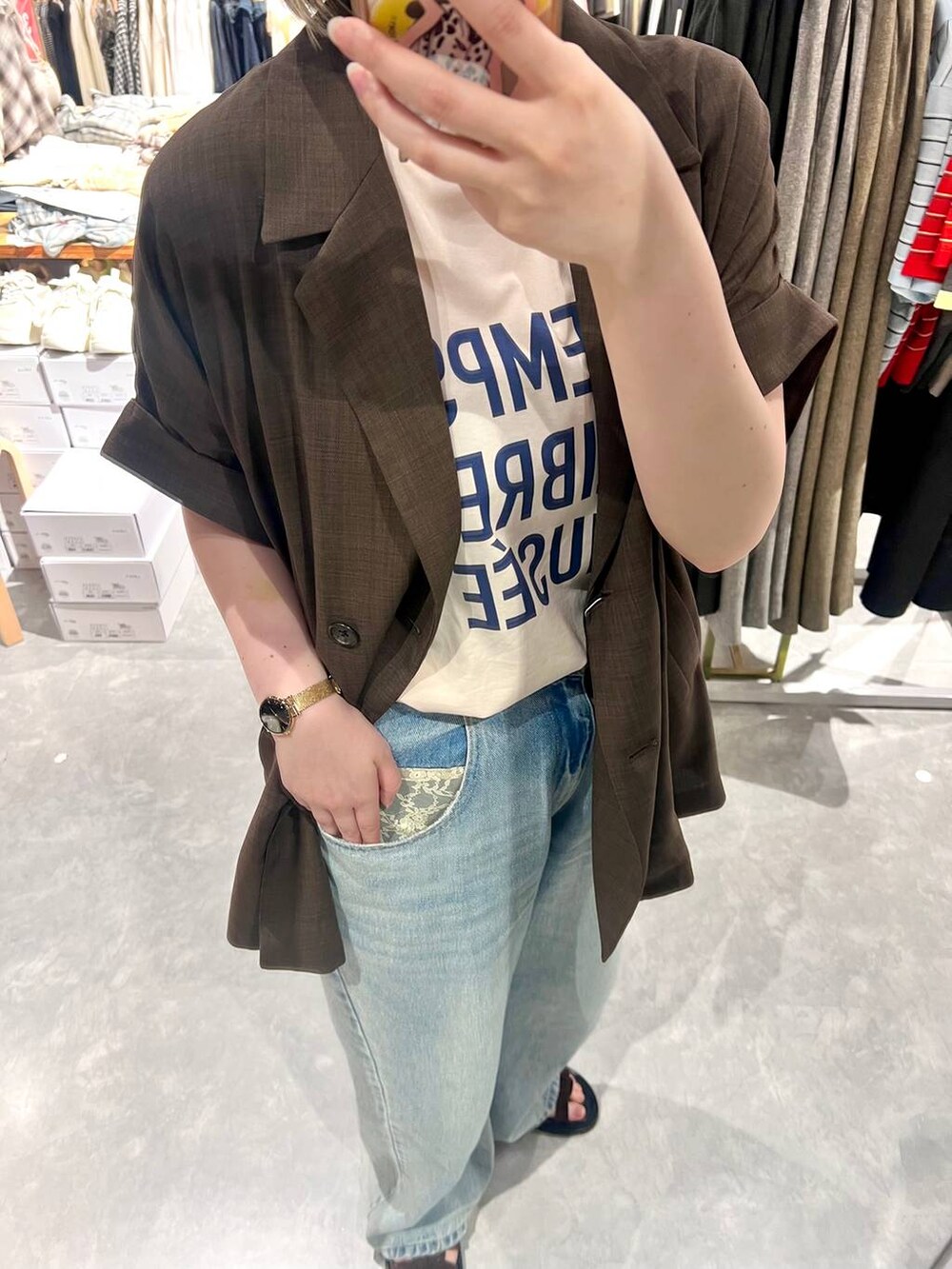 ブルー系のデニムパンツ、ブラウン系のテーラードジャケット、ブラウン系のサンダルを着用したレディースの春コーディネートの2枚目の写真