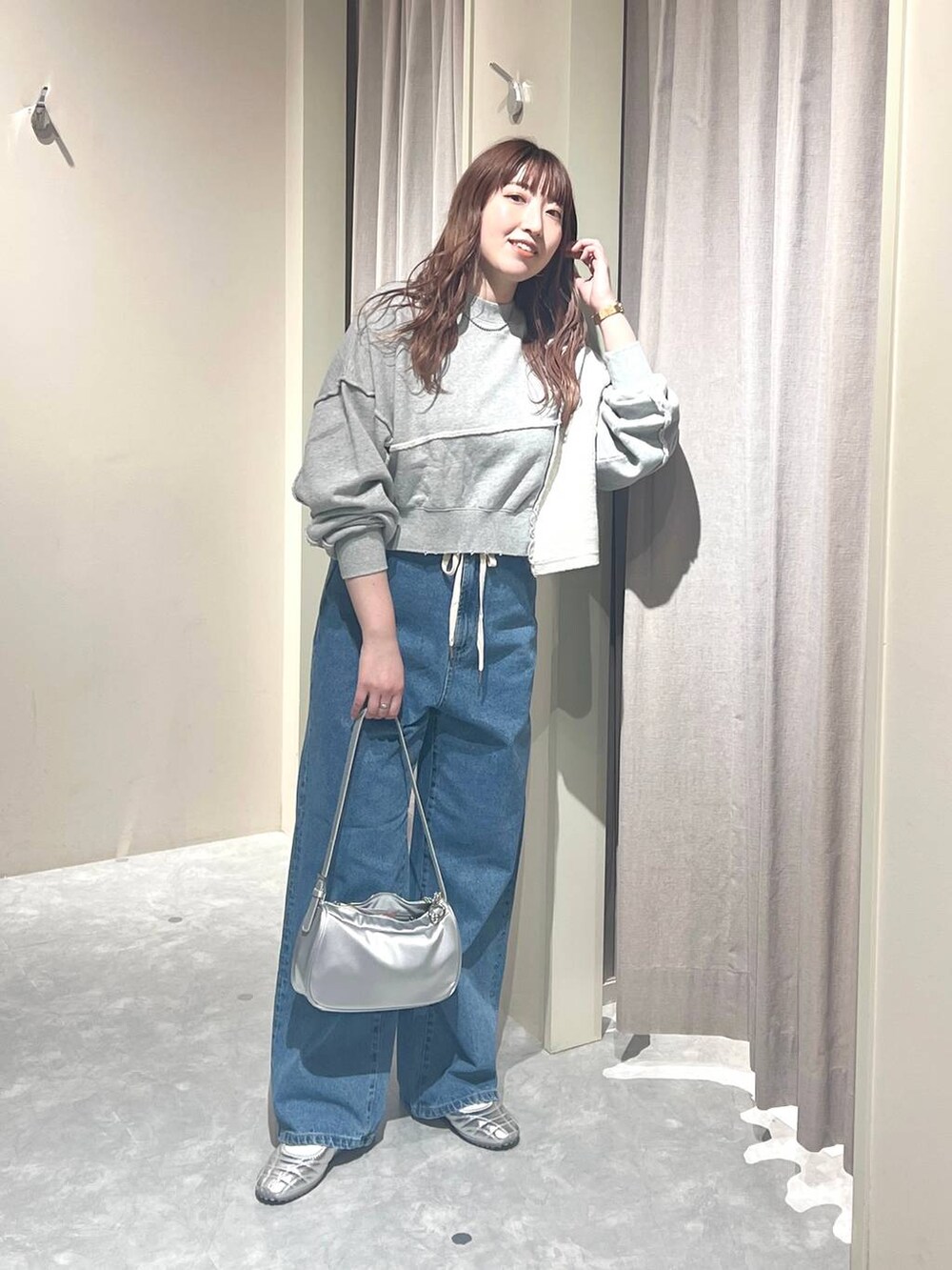グレー系のスウェット、ブルー系のデニムパンツ、シルバー系のトートバッグを着用したレディースの春コーディネートの5枚目の写真