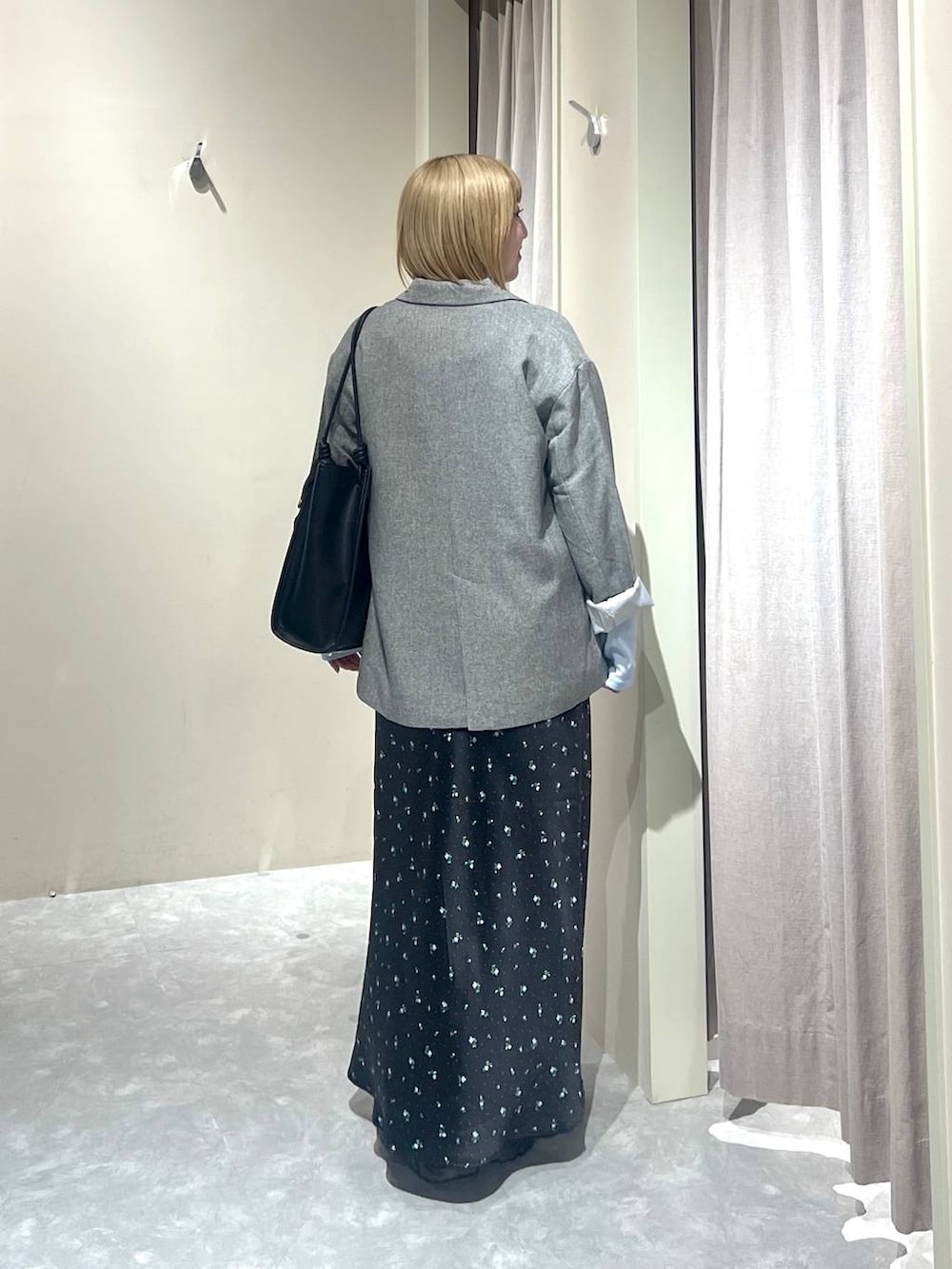 ブラック系のスカート、グレー系のテーラードジャケット、ブラック系のローファーを着用したレディースの春コーディネートの3枚目の写真