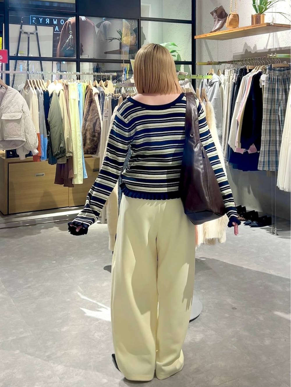 イエロー系のスウェットパンツ、ブラック系のパンプス、ブラウン系のショルダーバッグを着用したレディースの冬コーディネートの3枚目の写真