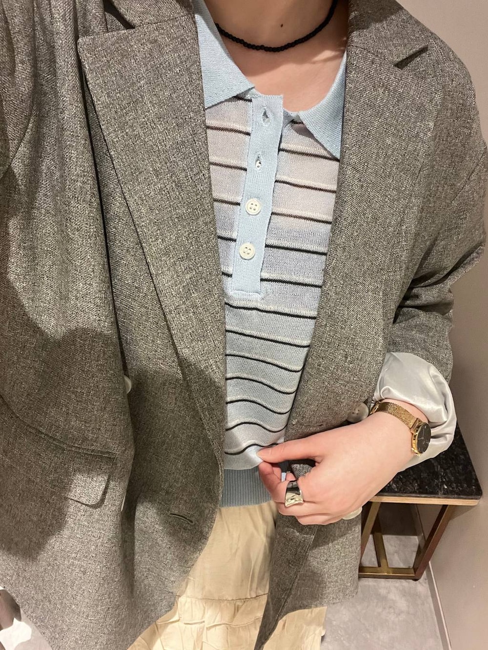 グレー系のテーラードジャケット、ホワイト系のスカート、ブルー系のポロシャツを着用したレディースの春コーディネートの4枚目の写真