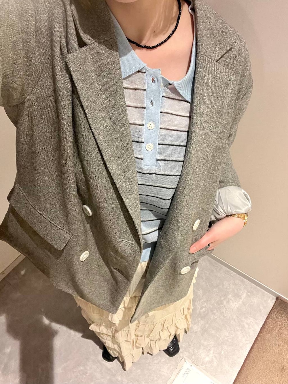 グレー系のテーラードジャケット、ホワイト系のスカート、ブルー系のポロシャツを着用したレディースの春コーディネートの6枚目の写真