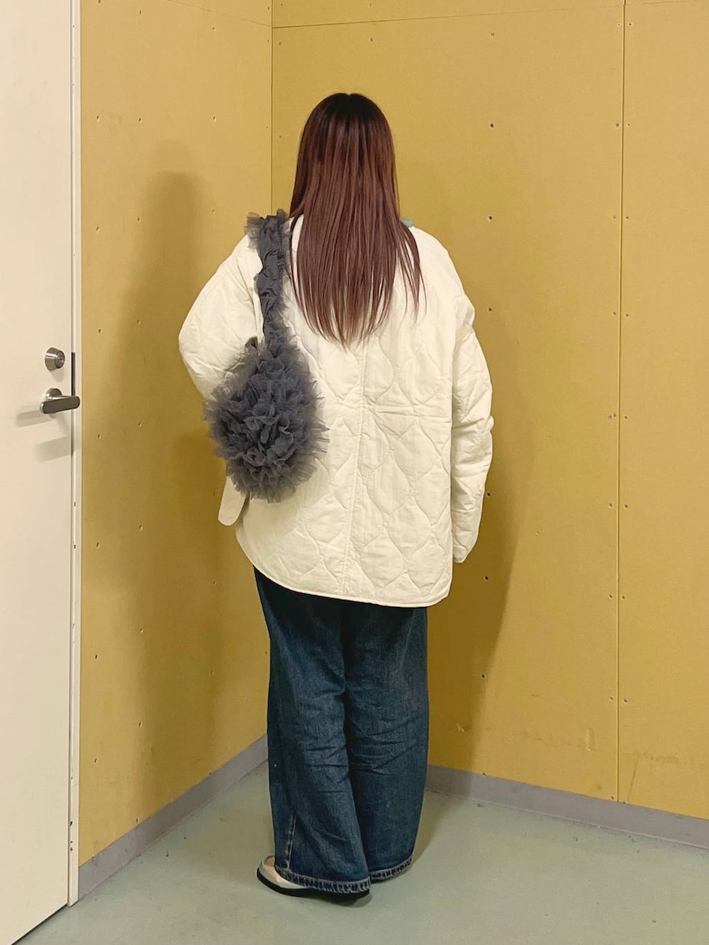 ホワイト系のブルゾン、ブルー系のデニムパンツ、シルバー系のローファーを着用したレディースの冬コーディネートの3枚目の写真