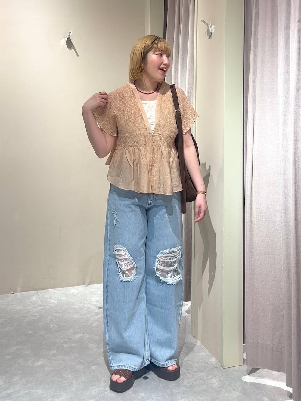 ブラウン系のショルダーバッグ、ブルー系のデニムパンツ、ブラウン系のサンダルを着用したレディースの春コーディネートの5枚目の写真