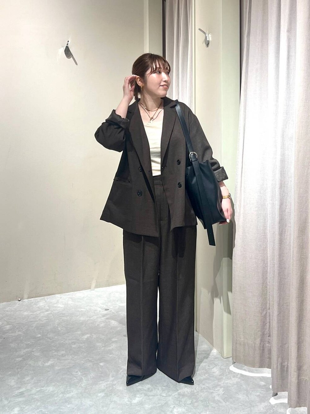 ブラウン系のテーラードジャケット、ブラウン系のその他パンツ、ホワイト系のキャミソールを着用したレディースの秋コーディネートの4枚目の写真