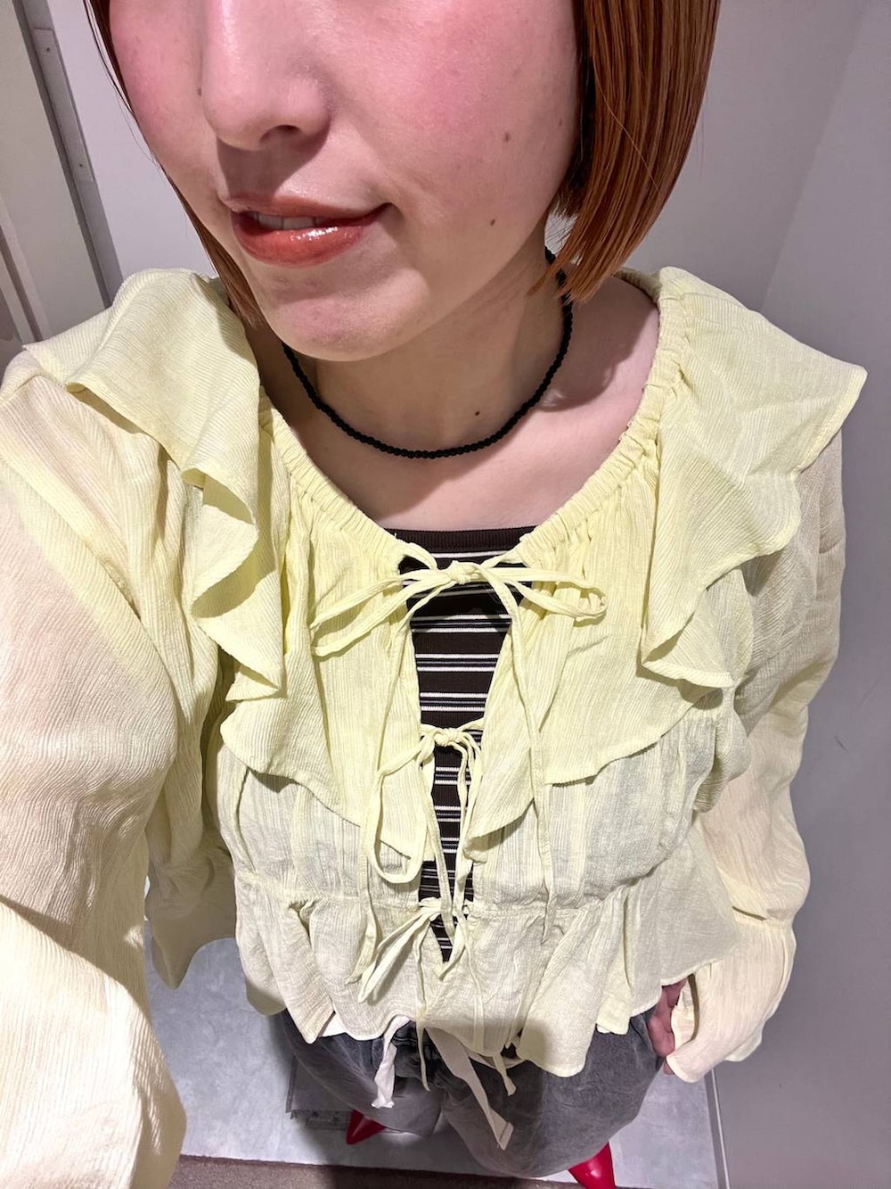 レッド系のパンプス、ブラック系のデニムパンツ、ブラウン系のタンクトップを着用したレディースの春コーディネートの4枚目の写真