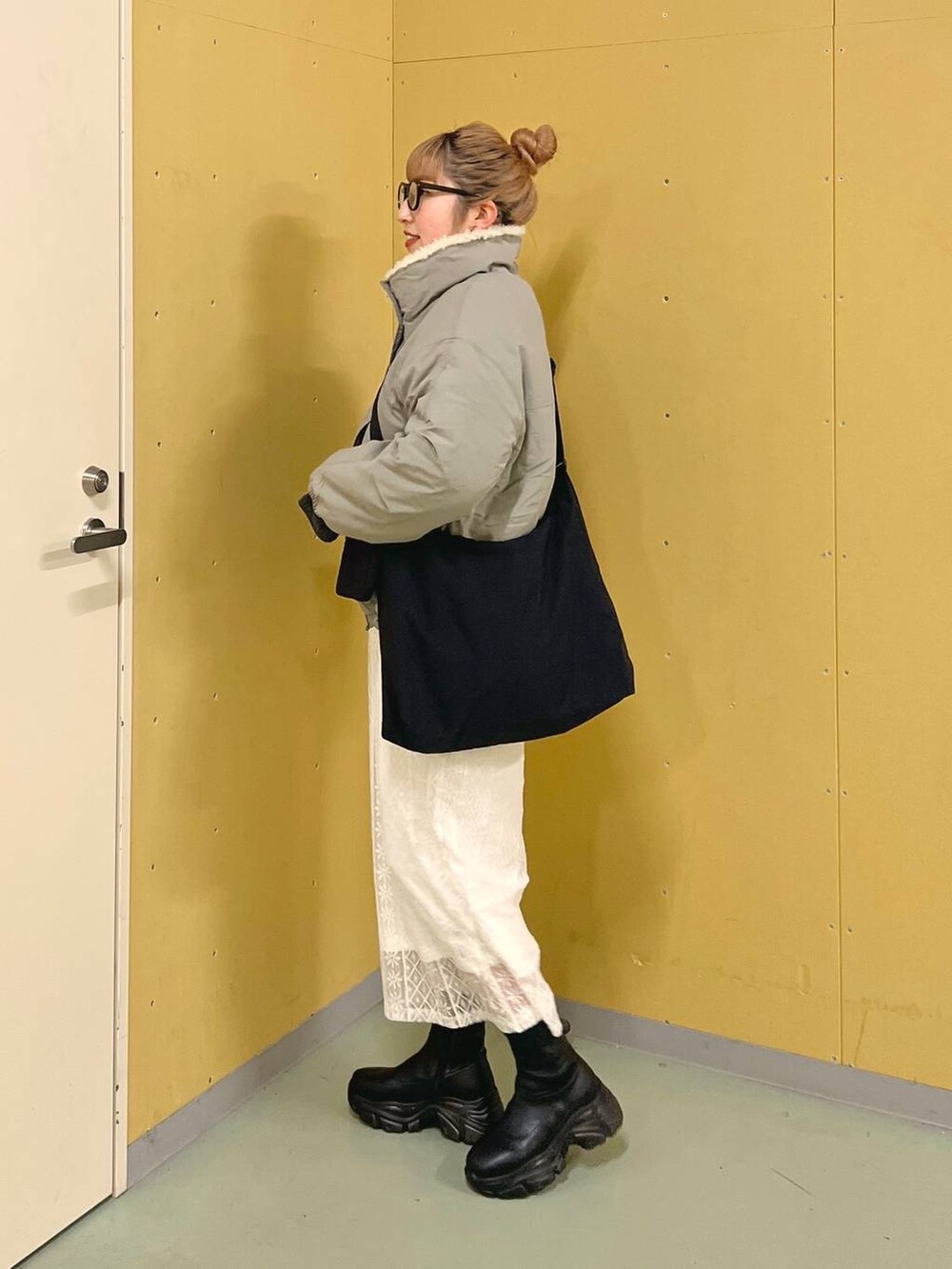 ブラック系のブーツ、ブルー系のワンピース、グリーン系のブルゾンを着用したレディースの冬コーディネートの2枚目の写真