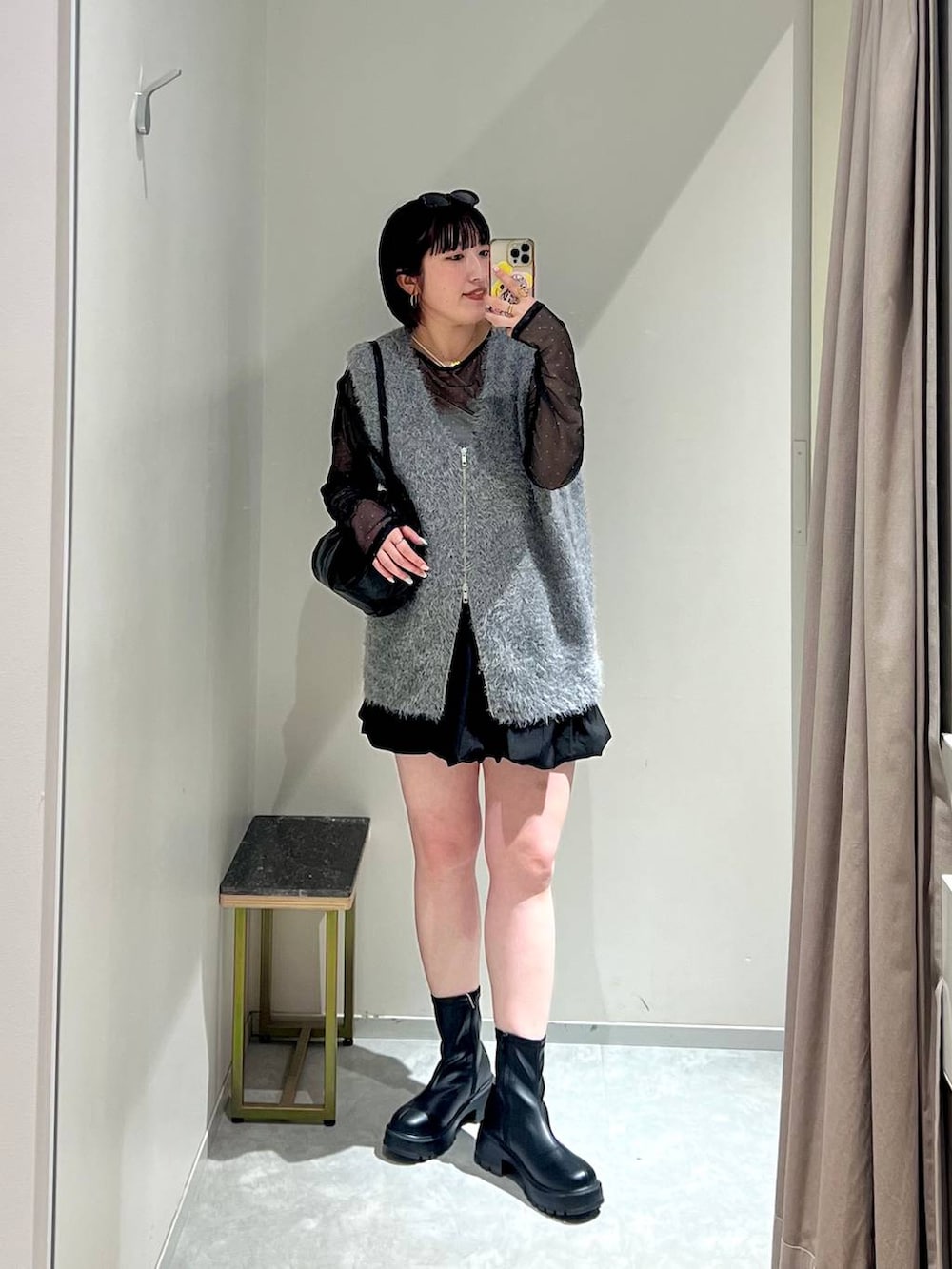 ブラック系のブーツ、ブラック系のボストンバッグ、グレー系のベストを着用したレディースの秋コーディネートの2枚目の写真