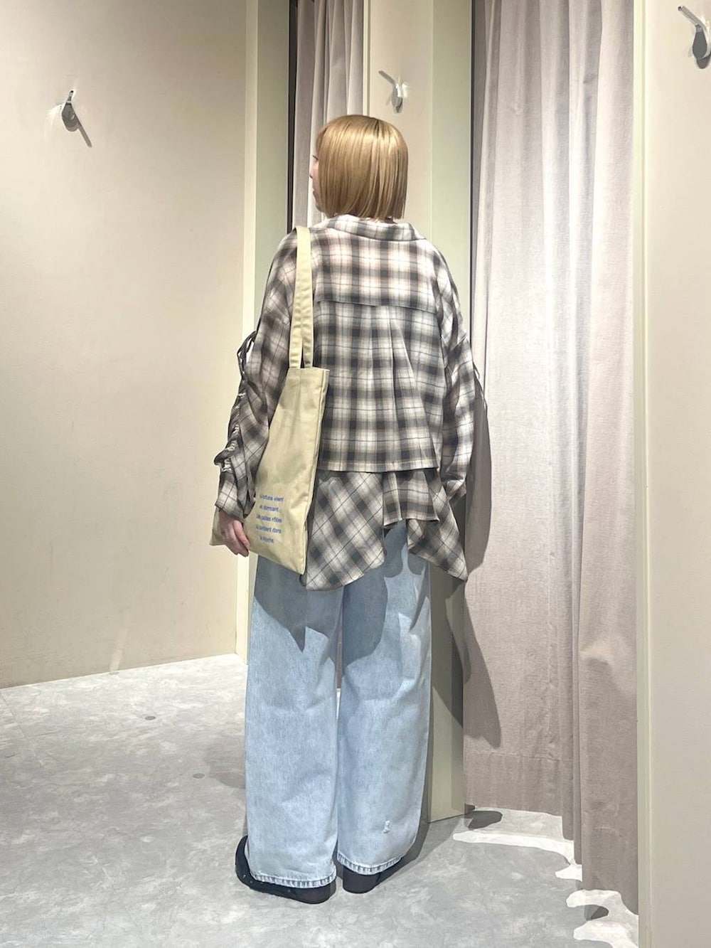 ブルー系のデニムパンツ、ベージュ系のトートバッグ、ブラック系のサンダルを着用したレディースの春コーディネートの3枚目の写真