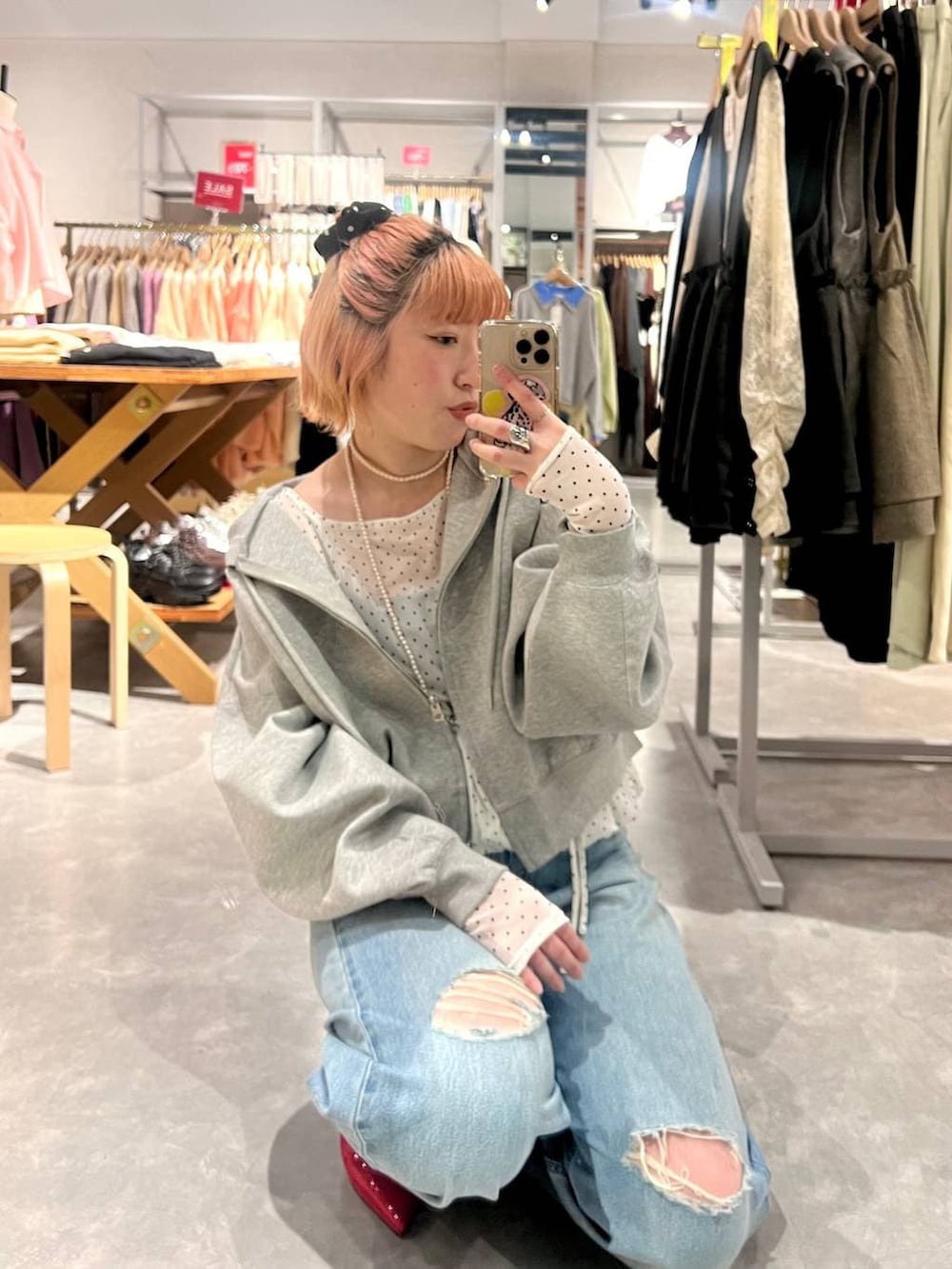 レッド系のパンプス、グレー系のパーカー、ブルー系のデニムパンツを着用したレディースの春コーディネートの2枚目の写真