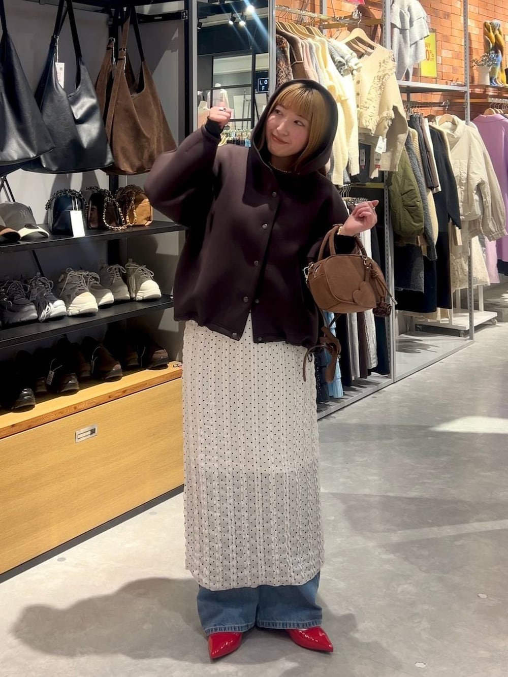 レッド系のパンプス、ブラウン系のボストンバッグ、ブルー系のデニムパンツを着用したレディースの春コーディネートの6枚目の写真