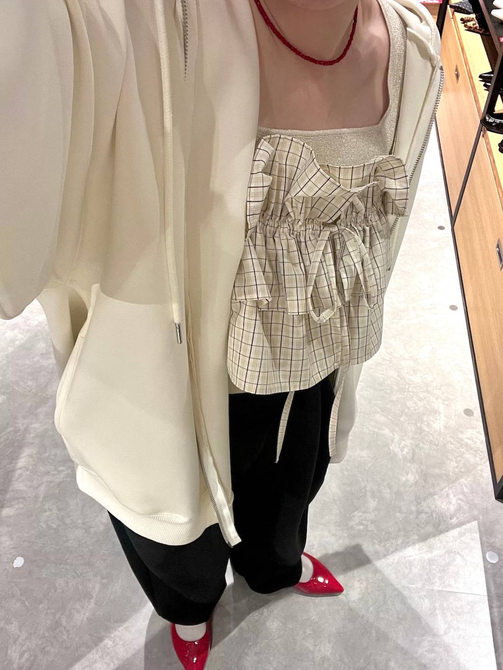 ブラック系のスウェットパンツ、ゴールド系のタンクトップ、ベージュ系のパーカーを着用したレディースの冬コーディネートの8枚目の写真