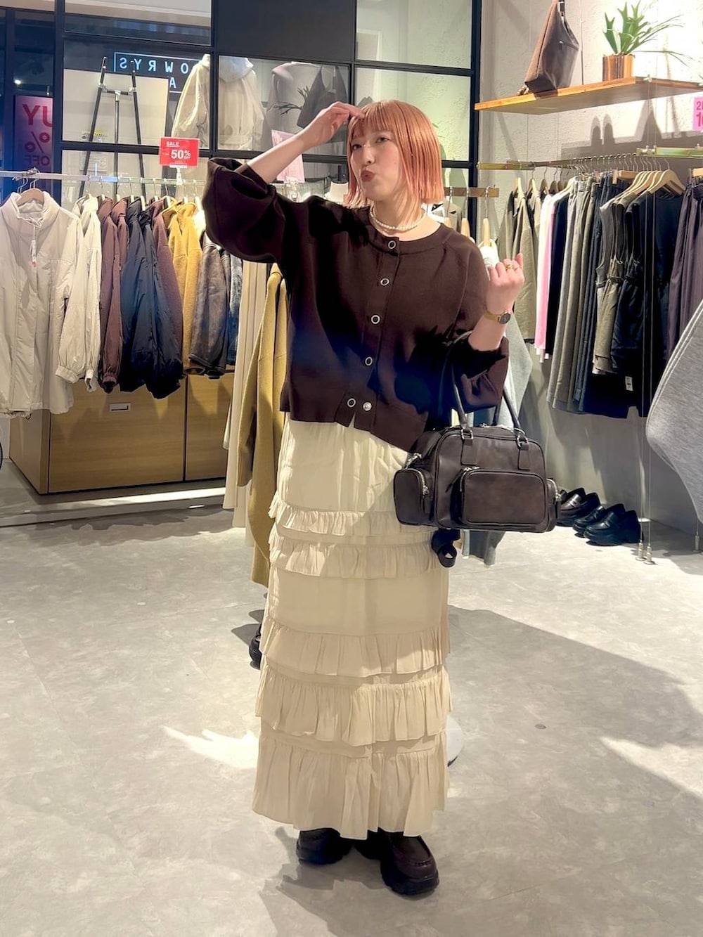 ブラウン系のボストンバッグ、ブラウン系のローファー、ホワイト系のスカートを着用したレディースの冬コーディネートの4枚目の写真