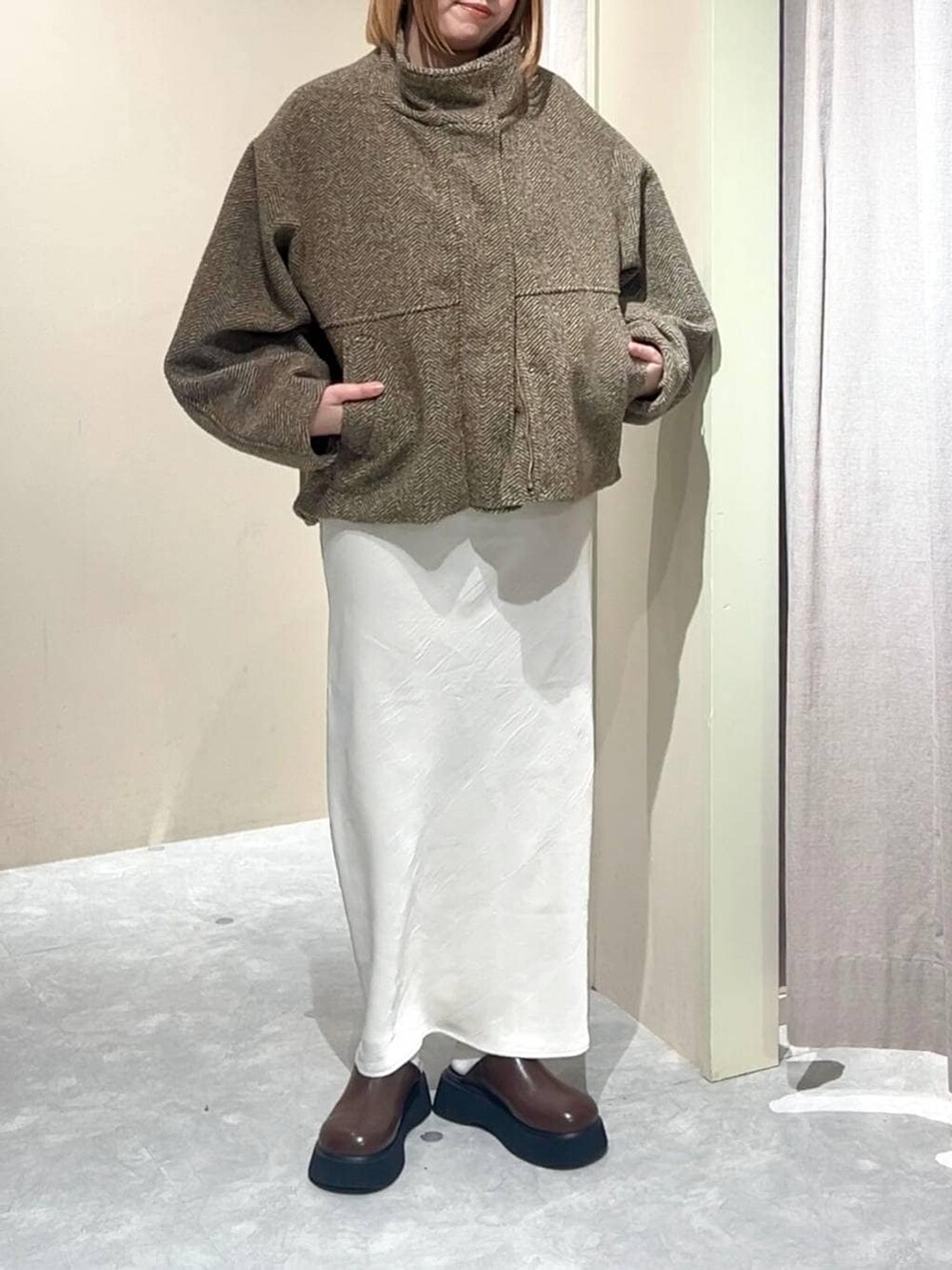 ホワイト系のスカート、ブラウン系のサンダル、ベージュ系のブルゾンを着用したレディースの冬コーディネートの2枚目の写真