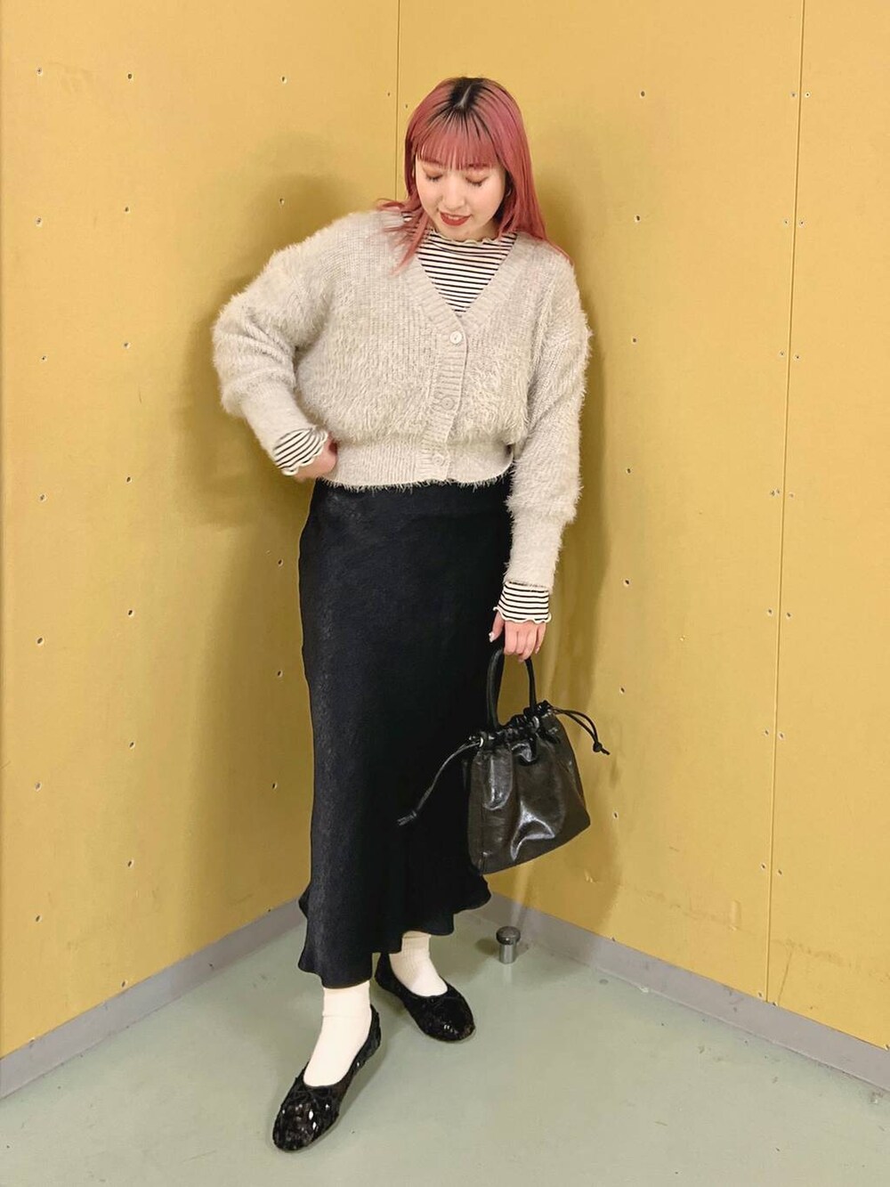 グレー系のニット/セーター、ホワイト系のTシャツ/カットソー、ブラック系のスカートを着用したレディースの春コーディネートの2枚目の写真