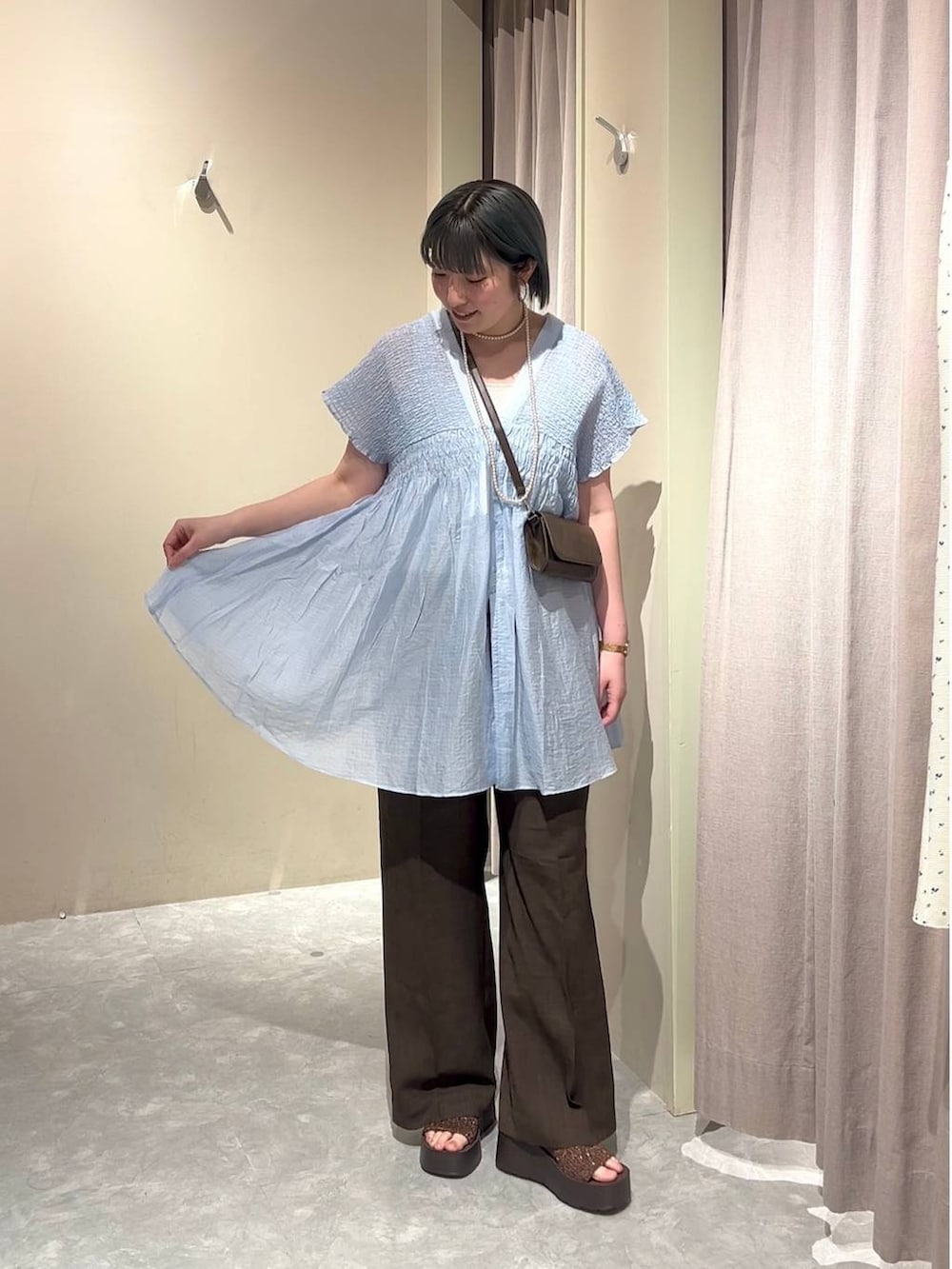 シルバー系のタンクトップ、ブルー系のシャツ/ブラウス、ブラウン系のスラックスを着用したレディースの春コーディネートの7枚目の写真