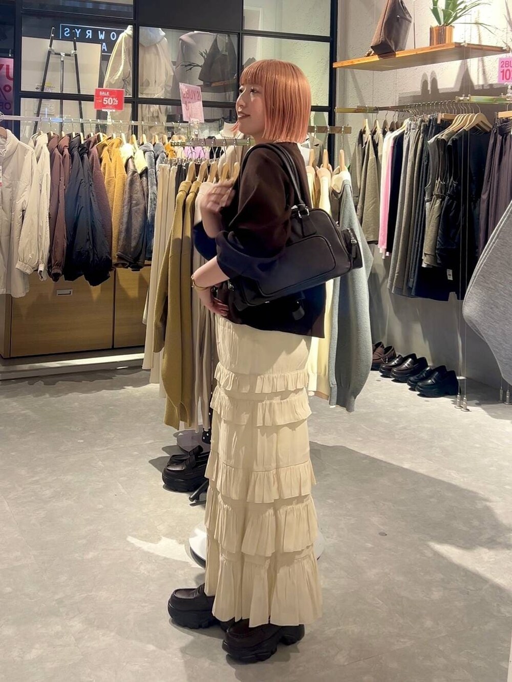 ブラウン系のボストンバッグ、ブラウン系のローファー、ホワイト系のスカートを着用したレディースの冬コーディネートの2枚目の写真