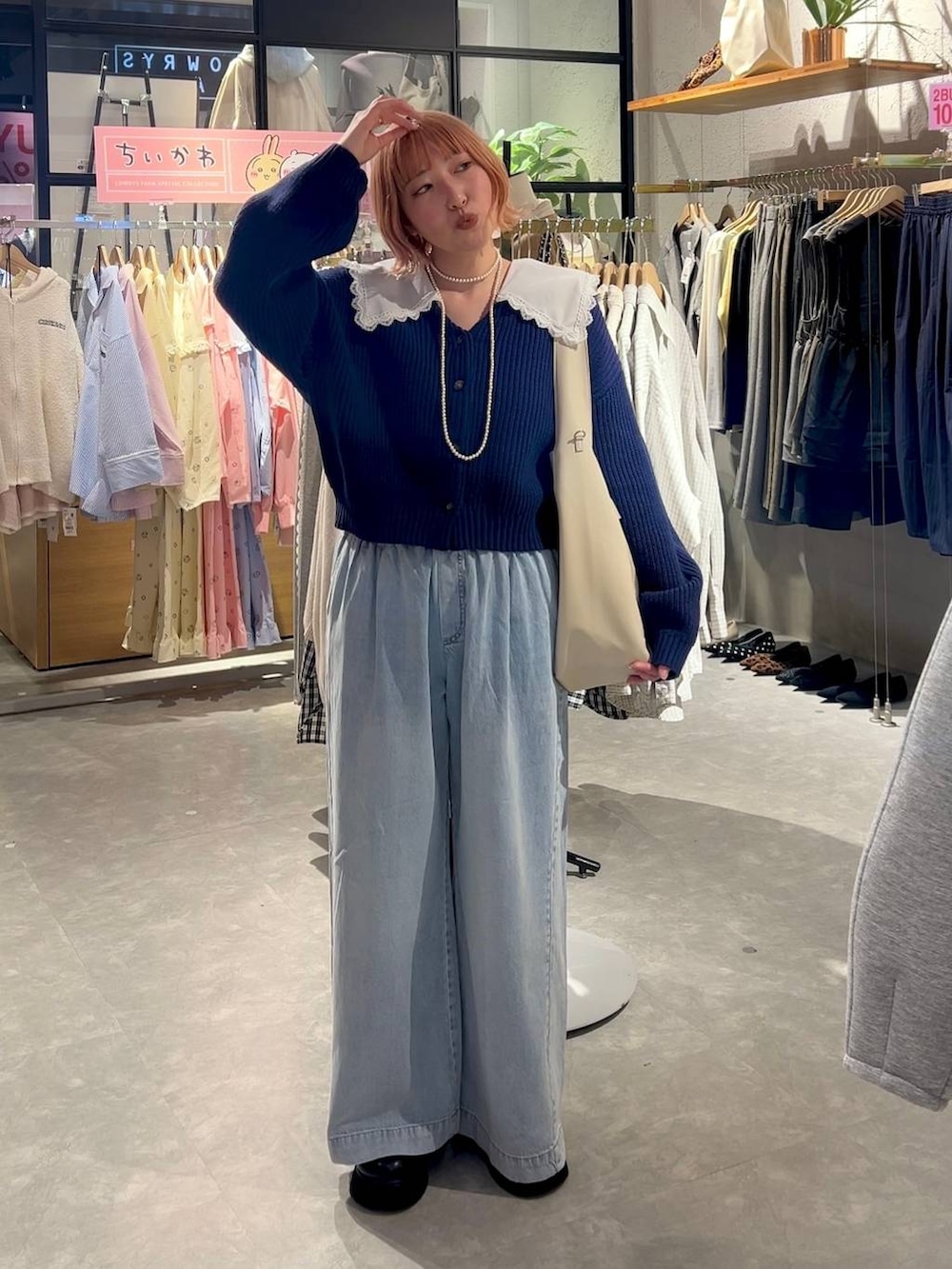 ブラック系のサンダル、ブルー系のデニムパンツ、ホワイト系のショルダーバッグを着用したレディースの冬コーディネートの2枚目の写真