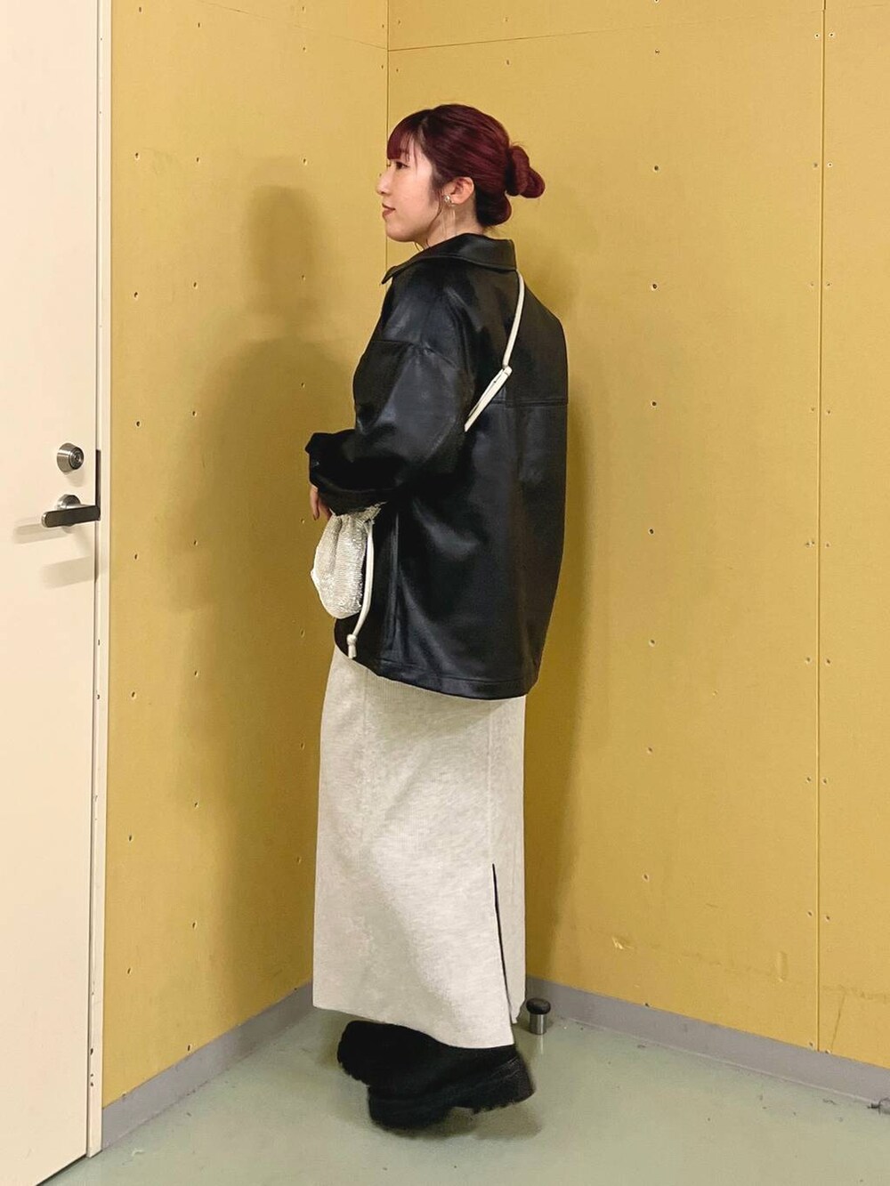 グレー系のスカート、ブラック系のブーツ、シルバー系のショルダーバッグを着用したレディースの秋コーディネートの2枚目の写真