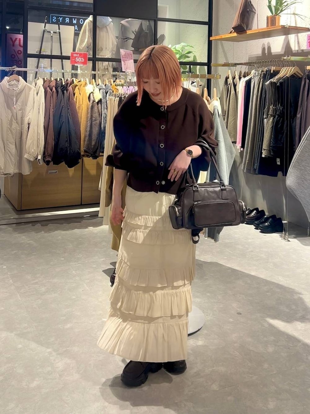 ブラウン系のボストンバッグ、ブラウン系のローファー、ホワイト系のスカートを着用したレディースの冬コーディネートの3枚目の写真