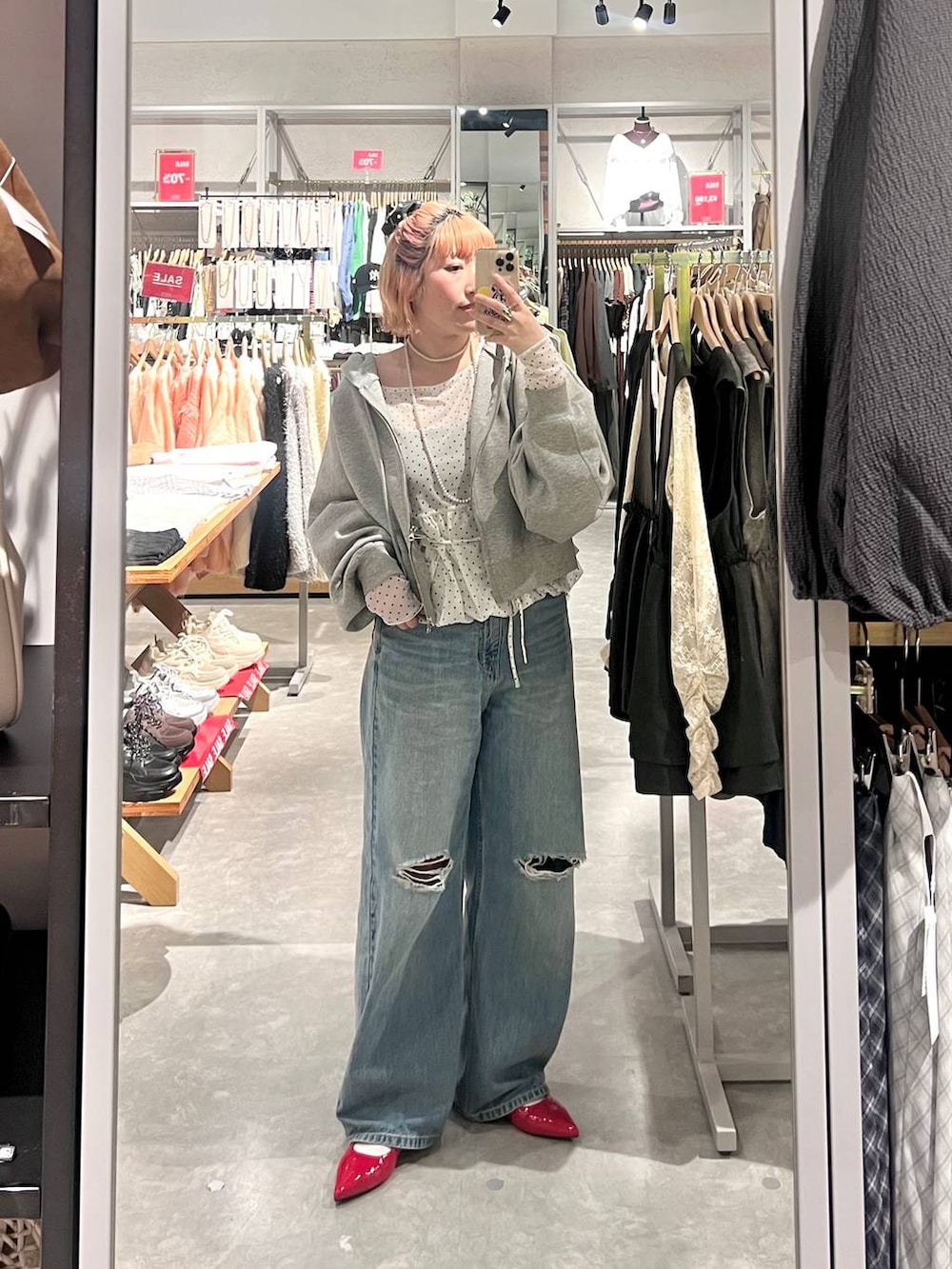 レッド系のパンプス、グレー系のパーカー、ブルー系のデニムパンツを着用したレディースの春コーディネートの5枚目の写真