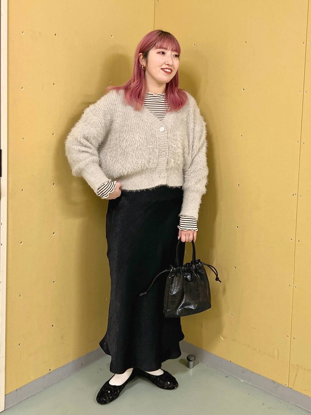 グレー系のニット/セーター、ホワイト系のTシャツ/カットソー、ブラック系のスカートを着用したレディースの春コーディネートの3枚目の写真