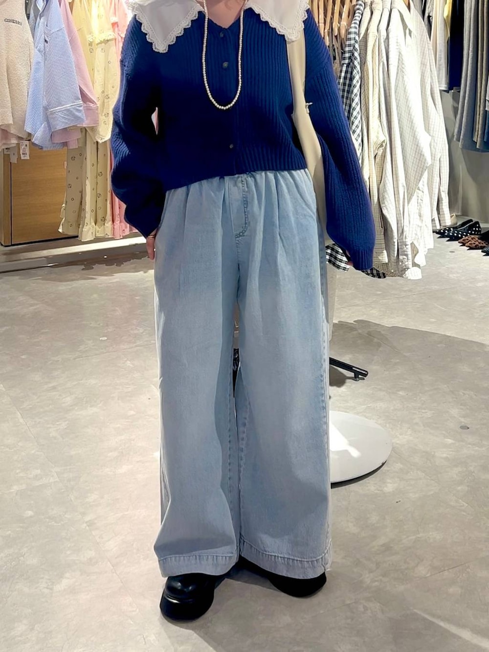 ブラック系のサンダル、ブルー系のデニムパンツ、ホワイト系のショルダーバッグを着用したレディースの冬コーディネートの3枚目の写真