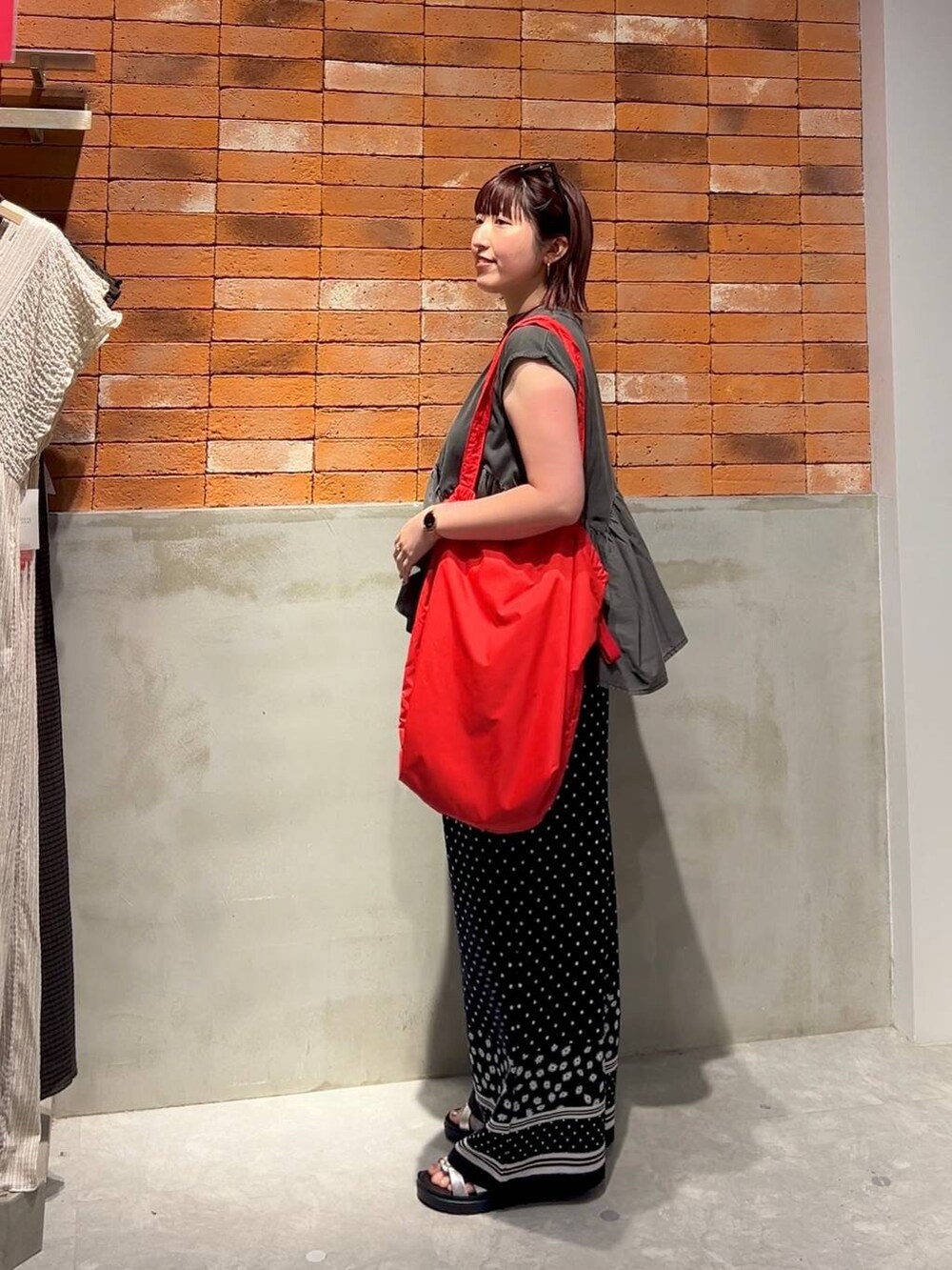 グレー系のTシャツ/カットソー、シルバー系のサンダル、レッド系のショルダーバッグを着用したレディースの夏コーディネートの2枚目の写真