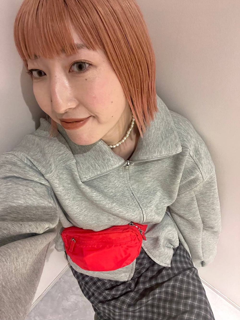 レッド系のボディバッグ/ウエストポーチ、グレー系のスカート、グレー系のスウェットを着用したレディースの冬コーディネートの3枚目の写真