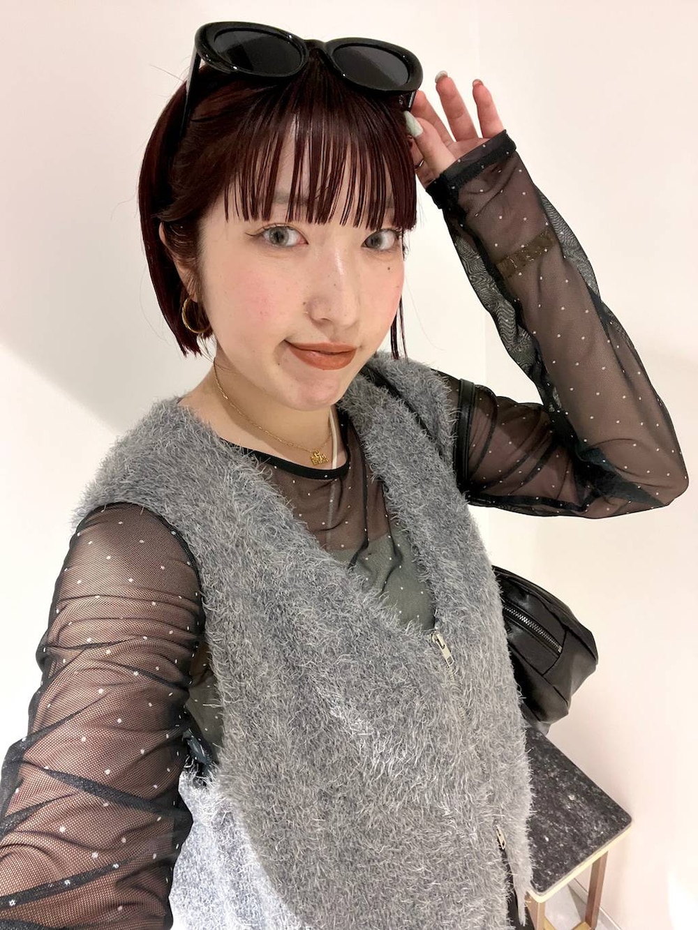 ブラック系のブーツ、ブラック系のボストンバッグ、グレー系のベストを着用したレディースの秋コーディネートの7枚目の写真