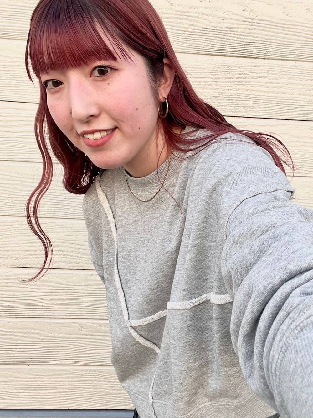 ブルー系のデニムパンツ、グレー系のスウェット、シルバー系のピアス(両耳用)を着用したレディースの秋コーディネートの4枚目の写真