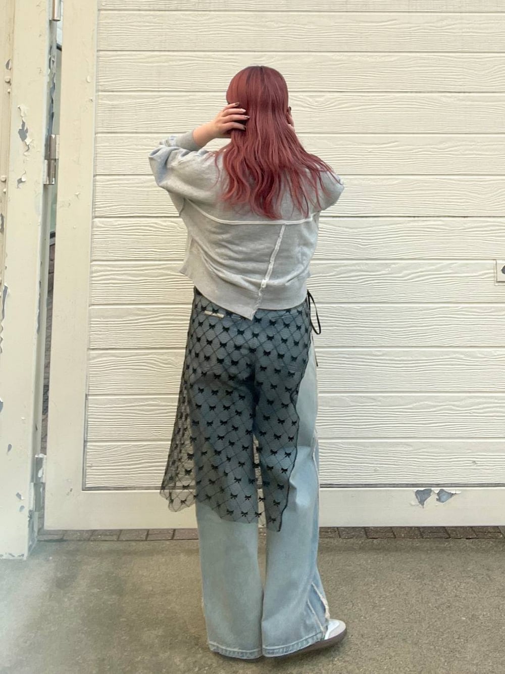 ブルー系のデニムパンツ、グレー系のスウェット、シルバー系のピアス(両耳用)を着用したレディースの秋コーディネートの3枚目の写真