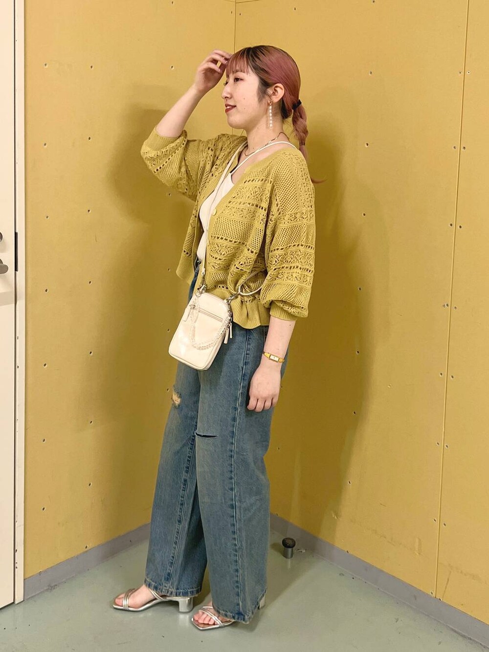 ベージュ系のショルダーバッグ、イエロー系のカーディガン/ボレロ、シルバー系のサンダルを着用したレディースの夏コーディネートの2枚目の写真