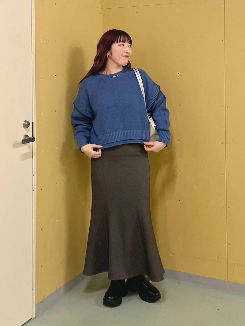 ブルー系のニット/セーター、ブラック系のブーツ、シルバー系のショルダーバッグを着用したレディースの冬コーディネートの4枚目の写真