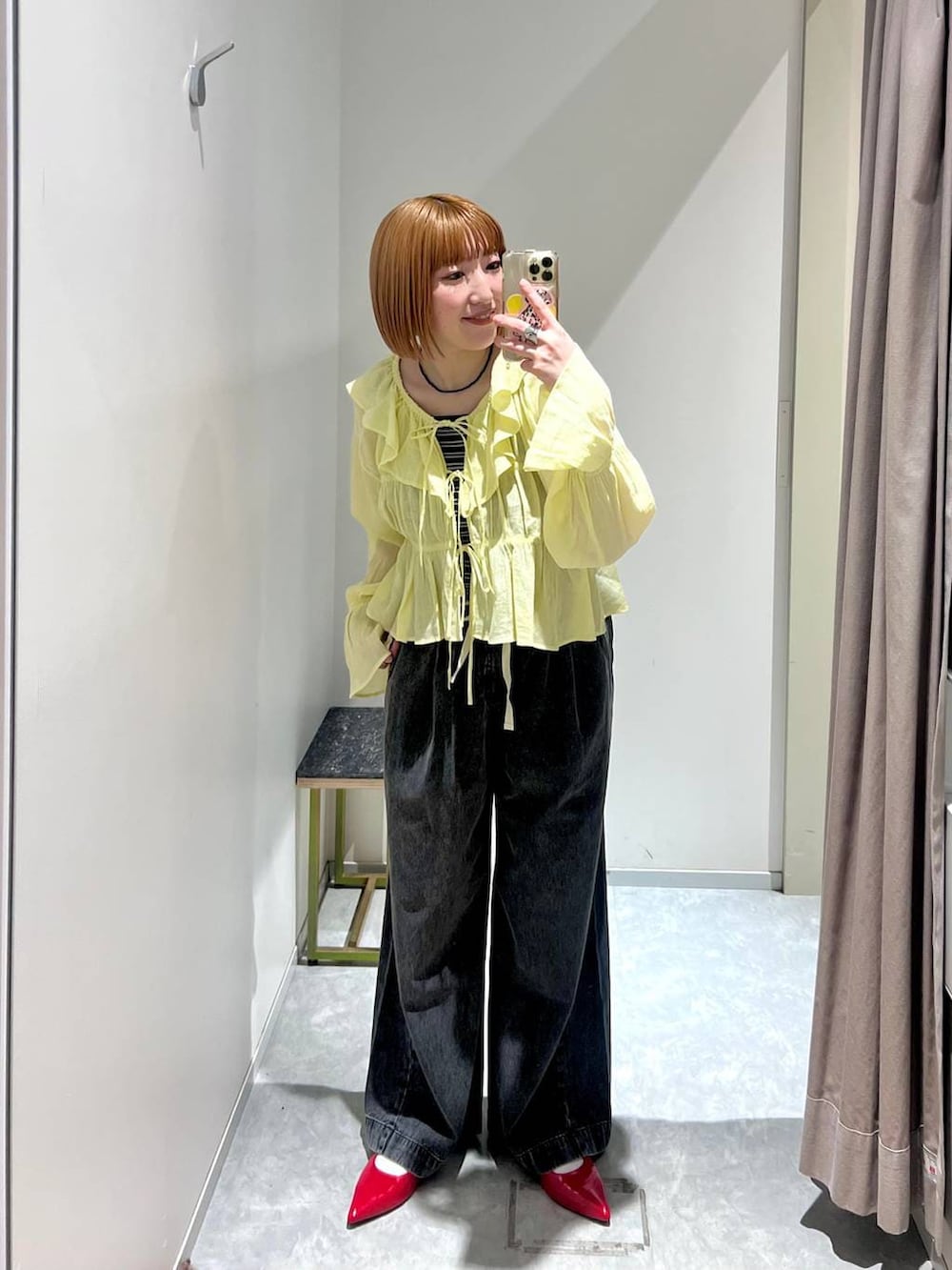 レッド系のパンプス、ブラック系のデニムパンツ、ブラウン系のタンクトップを着用したレディースの春コーディネートの3枚目の写真