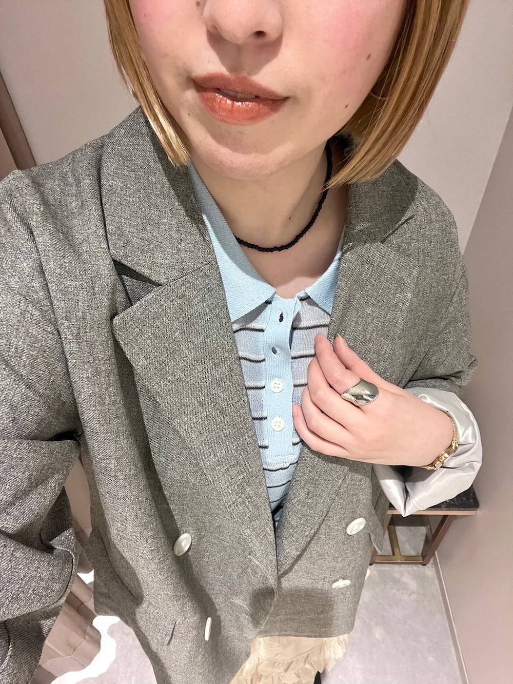 グレー系のテーラードジャケット、ホワイト系のスカート、ブルー系のポロシャツを着用したレディースの春コーディネートの2枚目の写真