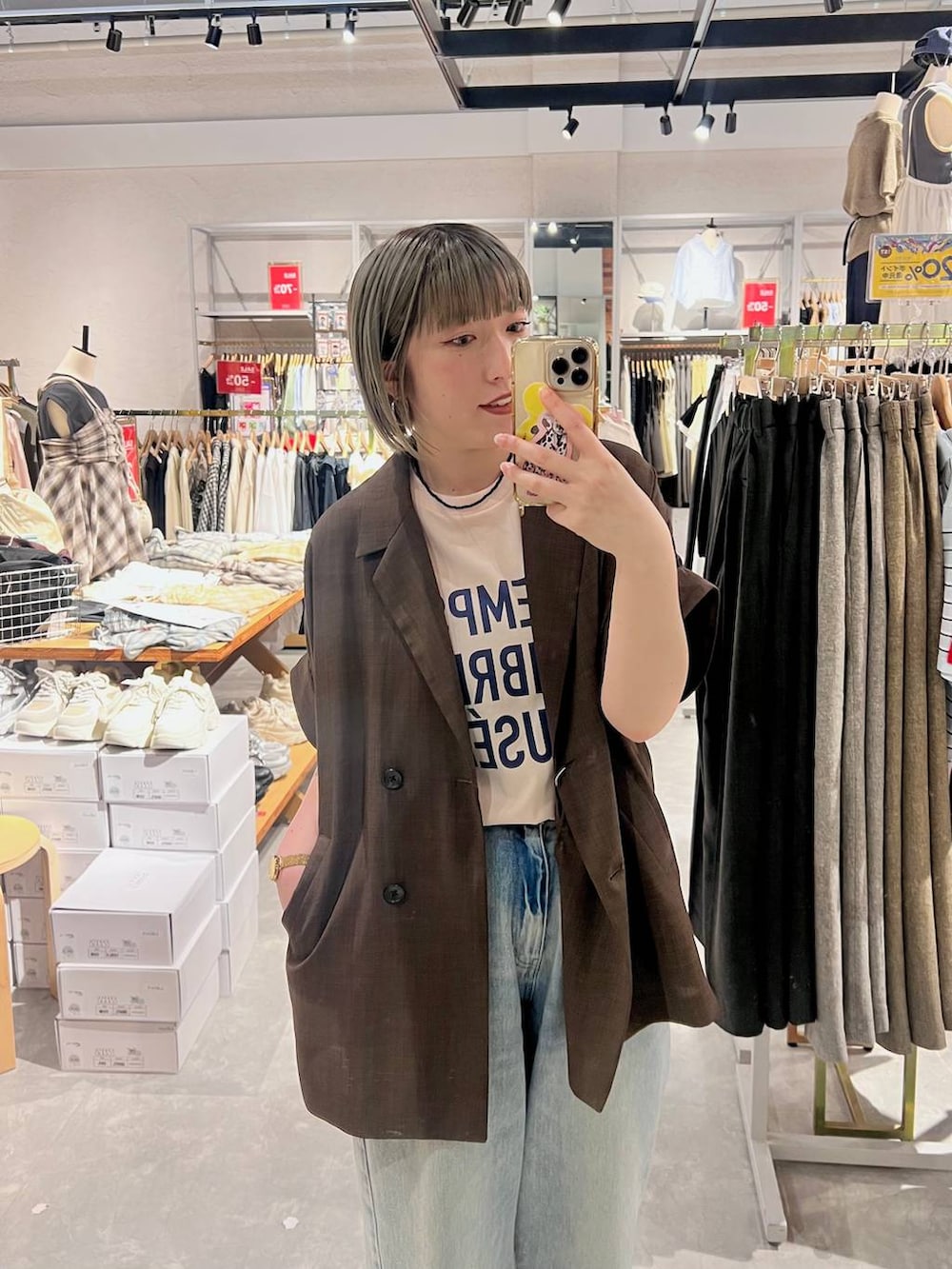 ブルー系のデニムパンツ、ブラウン系のテーラードジャケット、ブラウン系のサンダルを着用したレディースの春コーディネートの3枚目の写真