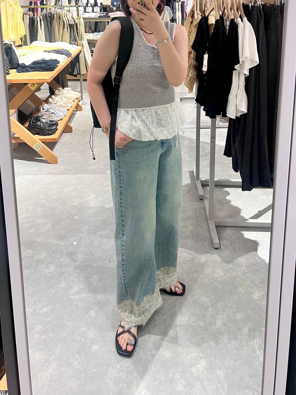 ブルー系のデニムパンツ、ブラック系のサンダル、グレー系のベストを着用したレディースの夏コーディネートの2枚目の写真