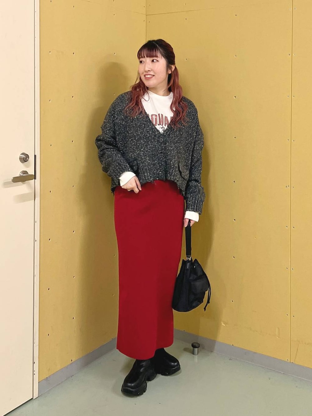 レッド系のスカート、ブラック系のショルダーバッグ、ブラック系のブーツを着用したレディースの秋コーディネートの5枚目の写真