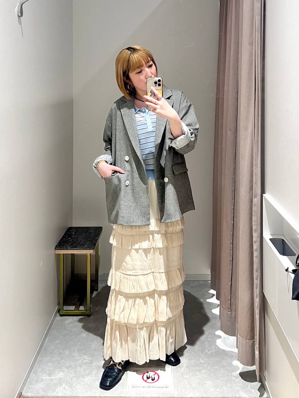 グレー系のテーラードジャケット、ホワイト系のスカート、ブルー系のポロシャツを着用したレディースの春コーディネートの7枚目の写真