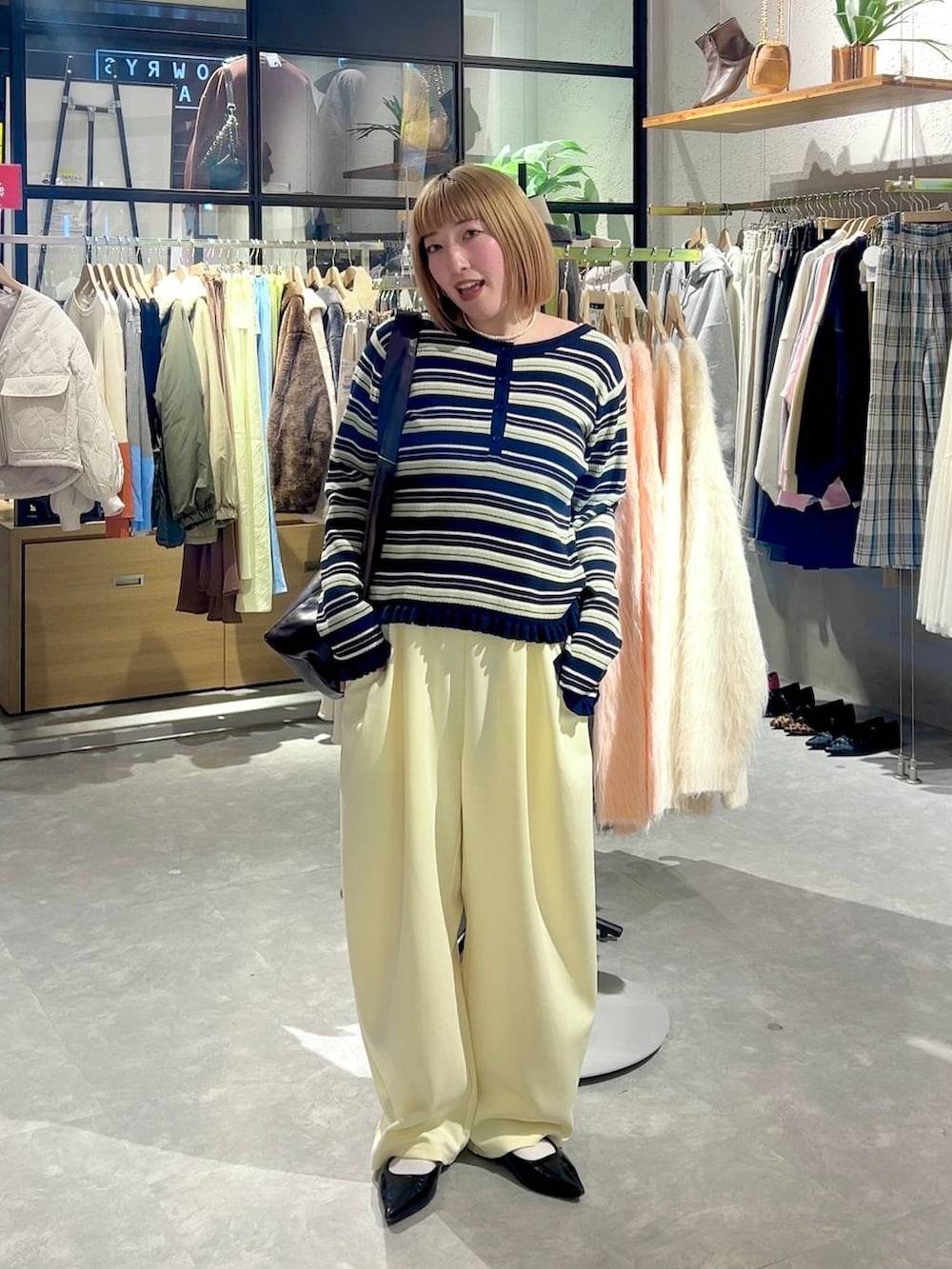 イエロー系のスウェットパンツ、ブラック系のパンプス、ブラウン系のショルダーバッグを着用したレディースの冬コーディネートの4枚目の写真