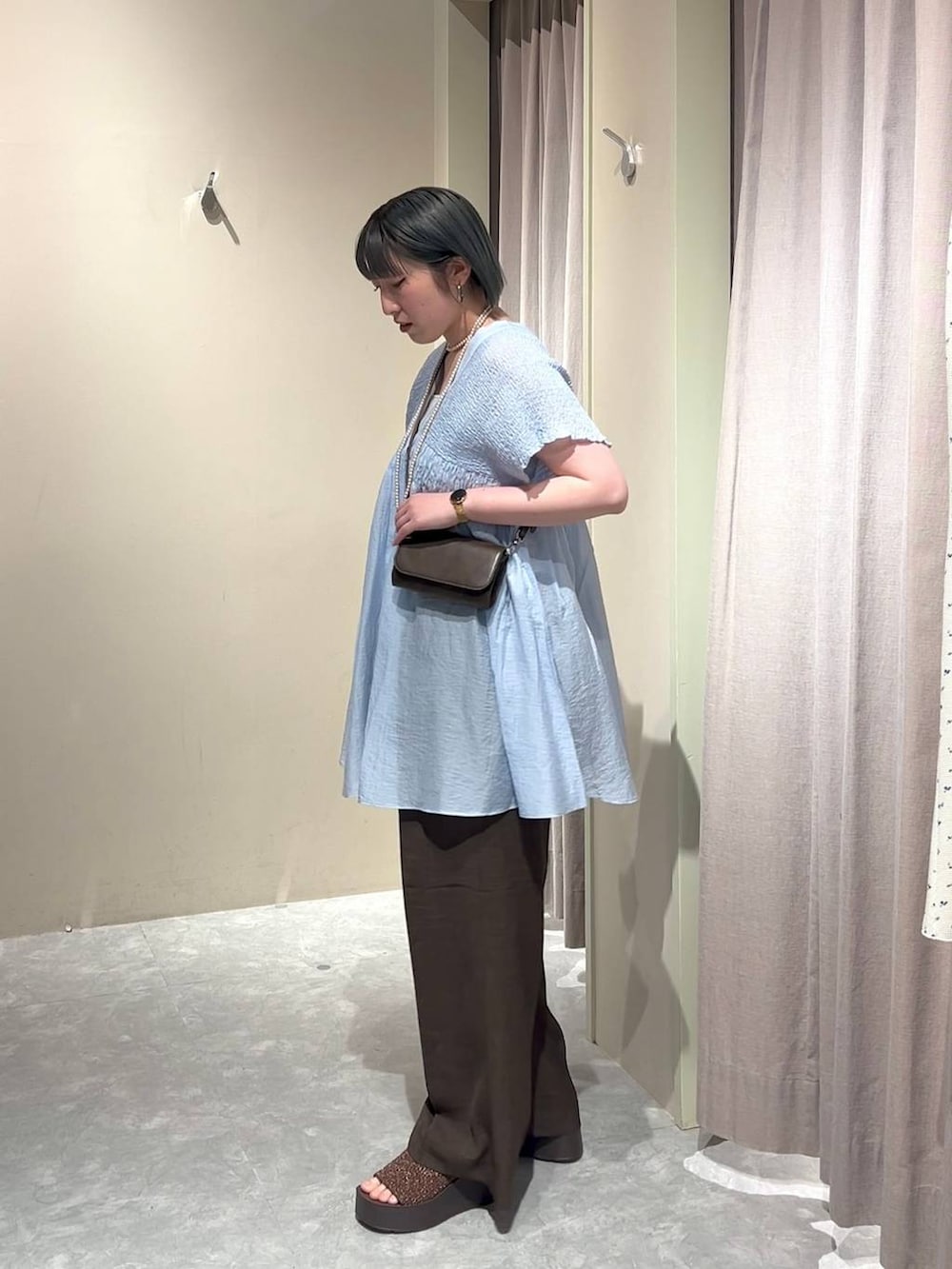 シルバー系のタンクトップ、ブルー系のシャツ/ブラウス、ブラウン系のスラックスを着用したレディースの春コーディネートの2枚目の写真