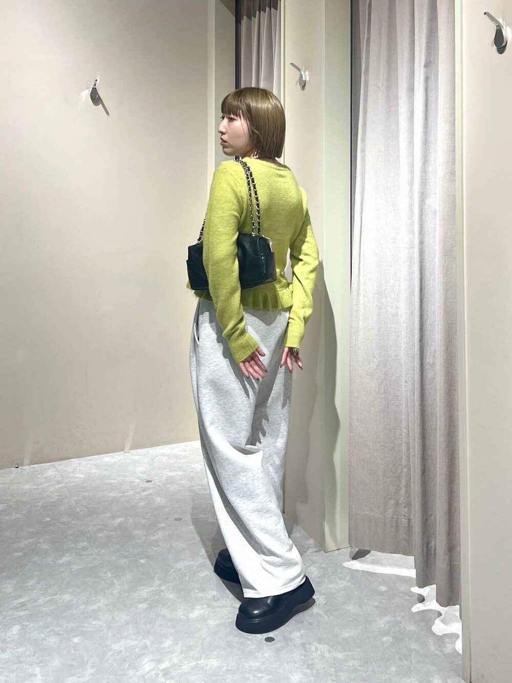 グレー系のスウェットパンツ、ブラック系のサンダル、イエロー系のニット/セーターを着用したレディースの秋コーディネートの2枚目の写真