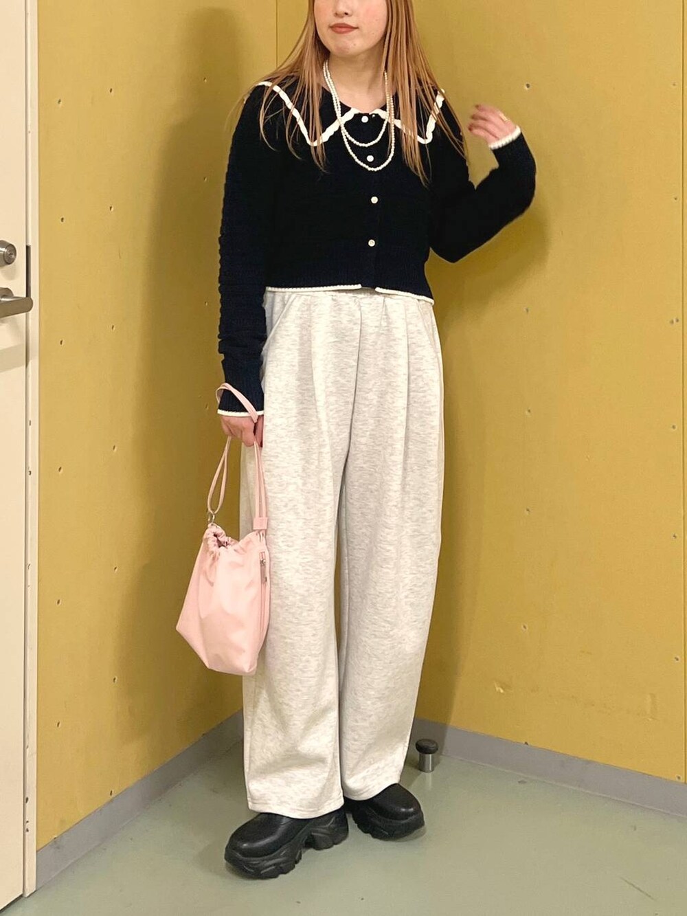 ブラック系のブーツ、ピンク系のショルダーバッグ、ブルー系のニット/セーターを着用したレディースの冬コーディネートの3枚目の写真