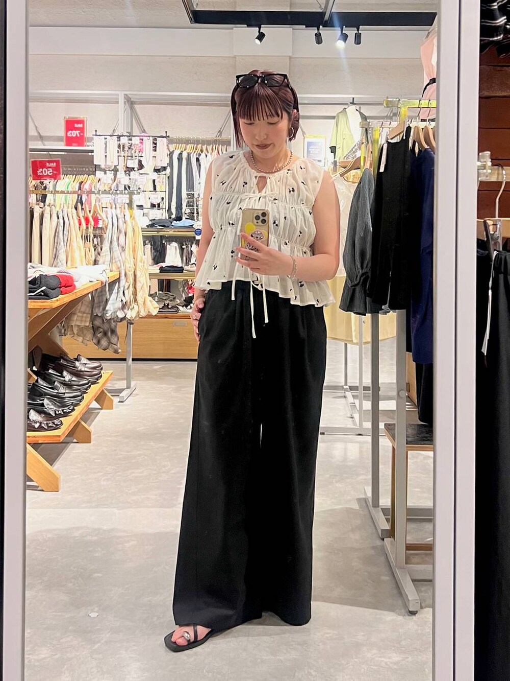 ブラック系のデニムパンツ、ブラック系のサンダル、ホワイト系のシャツ/ブラウスを着用したレディースの夏コーディネートの6枚目の写真