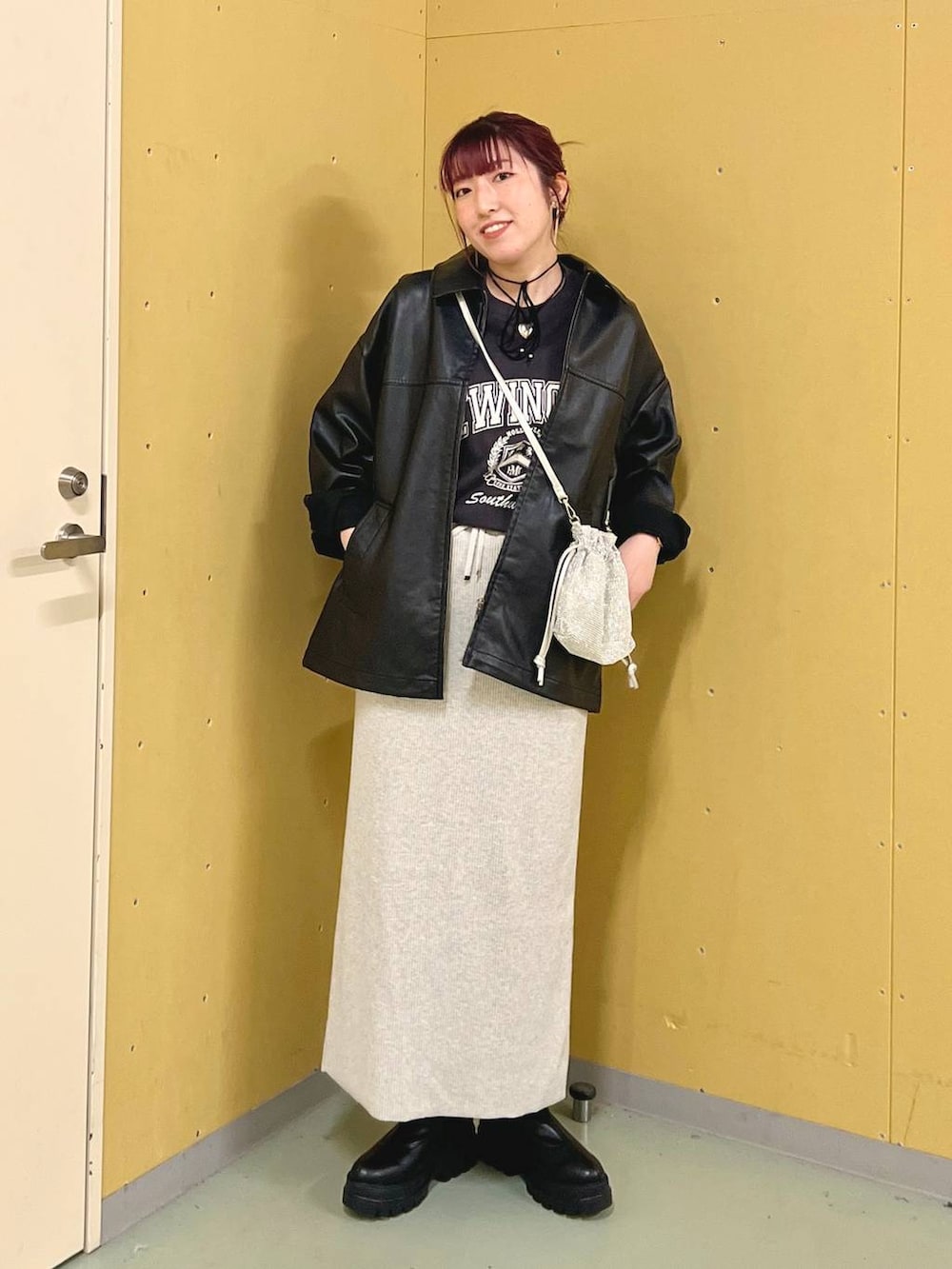 グレー系のスカート、ブラック系のブーツ、シルバー系のショルダーバッグを着用したレディースの秋コーディネートの4枚目の写真