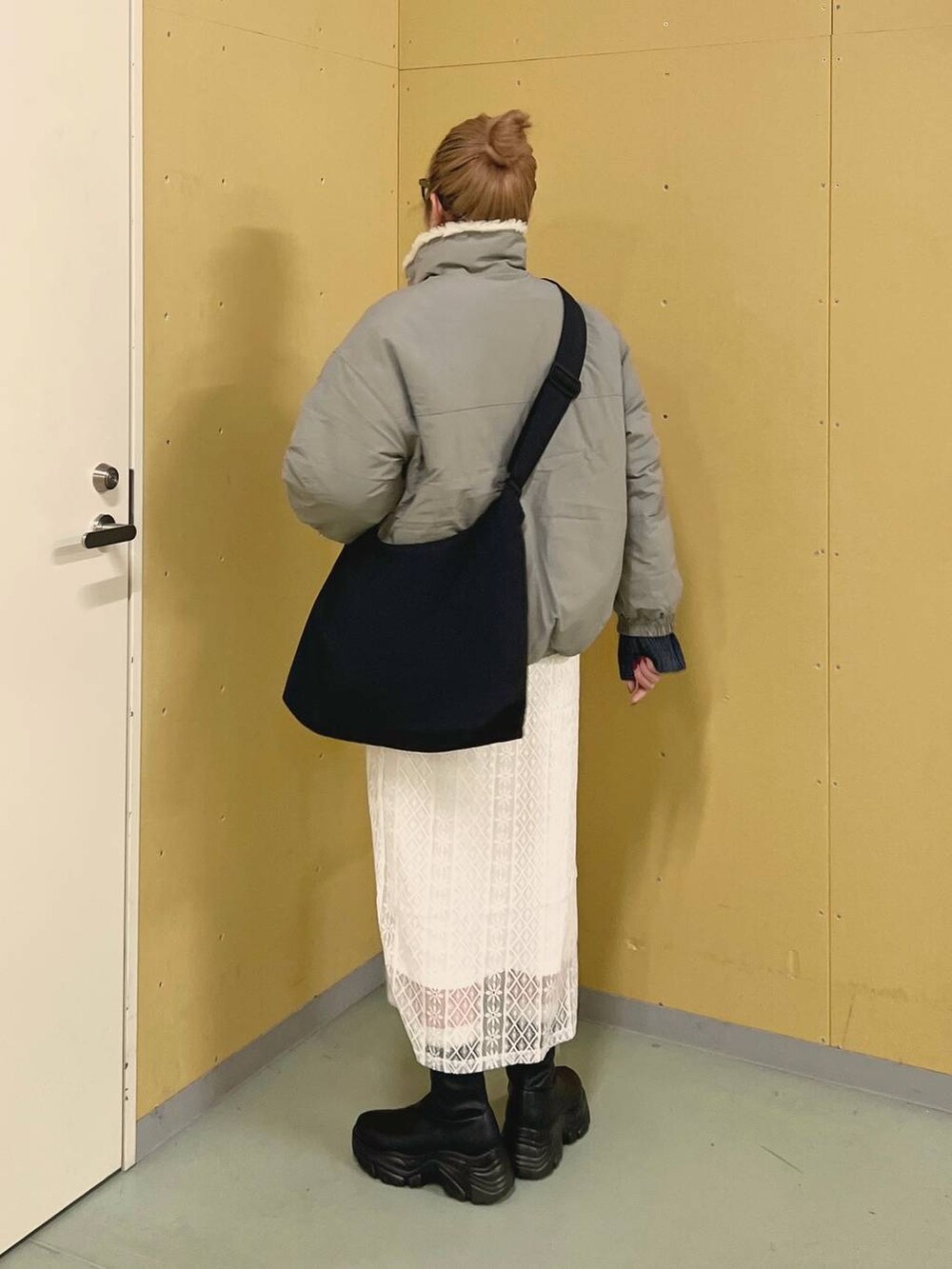 ブラック系のブーツ、ブルー系のワンピース、グリーン系のブルゾンを着用したレディースの冬コーディネートの3枚目の写真