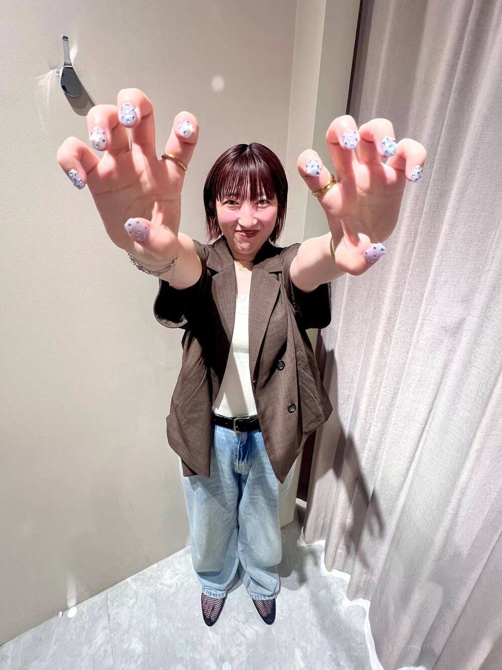 ブルー系のデニムパンツ、ブラウン系のテーラードジャケット、ホワイト系のキャミソールを着用したレディースの夏コーディネートの2枚目の写真