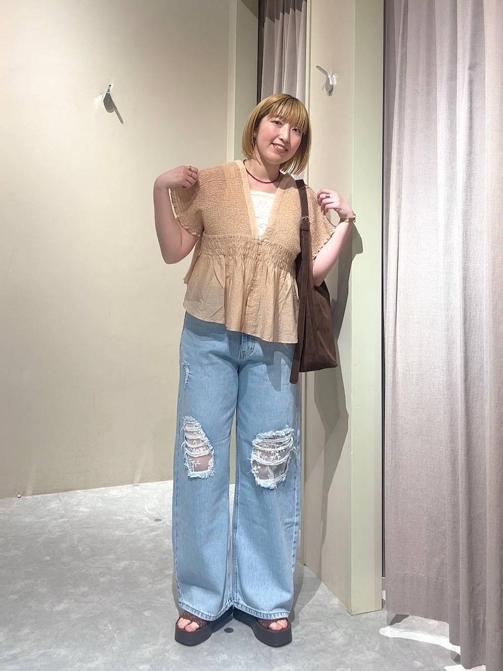 ブラウン系のショルダーバッグ、ブルー系のデニムパンツ、ブラウン系のサンダルを着用したレディースの春コーディネートの6枚目の写真